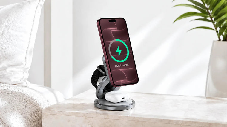 Burgundy iPhone, Apple Watch and white earbuds on a foldable charger beside a bed.