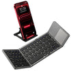 A compact foldable wireless keyboard shown open on a white background, with a smartphone propped in the back on a small stand. The keyboard has a dark gray and black design with a touchpad on the right side.