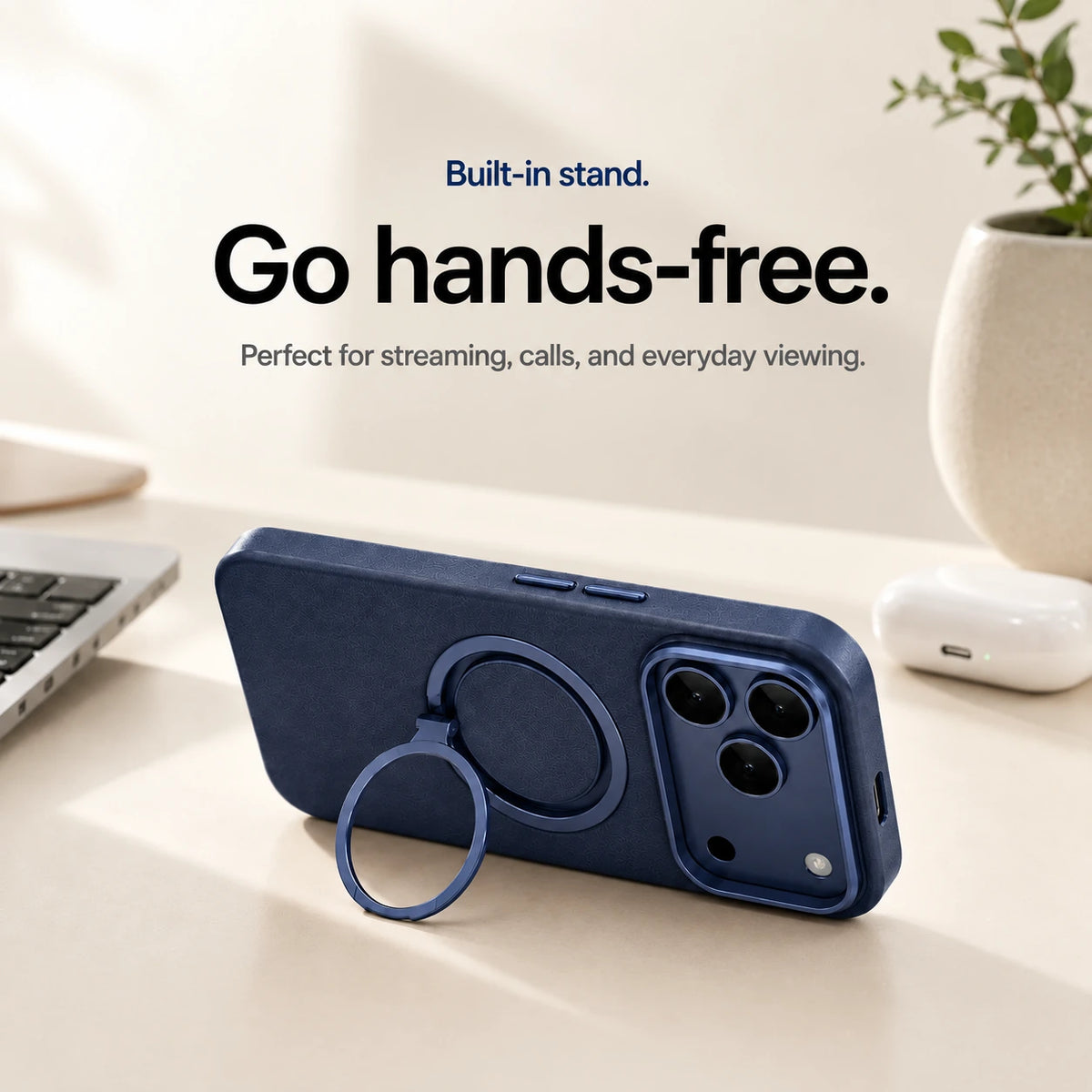 Navy blue leather phone case propped horizontally on its ring stand beside a laptop #color_Deep Blue